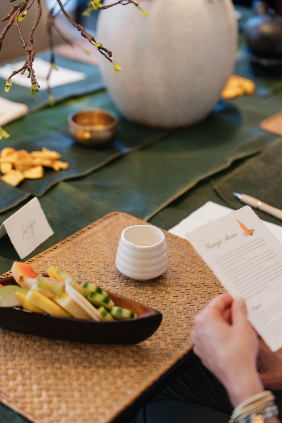 Rujak buah and a ceramic cup beside a kunyit asam recipe card at the tasting table