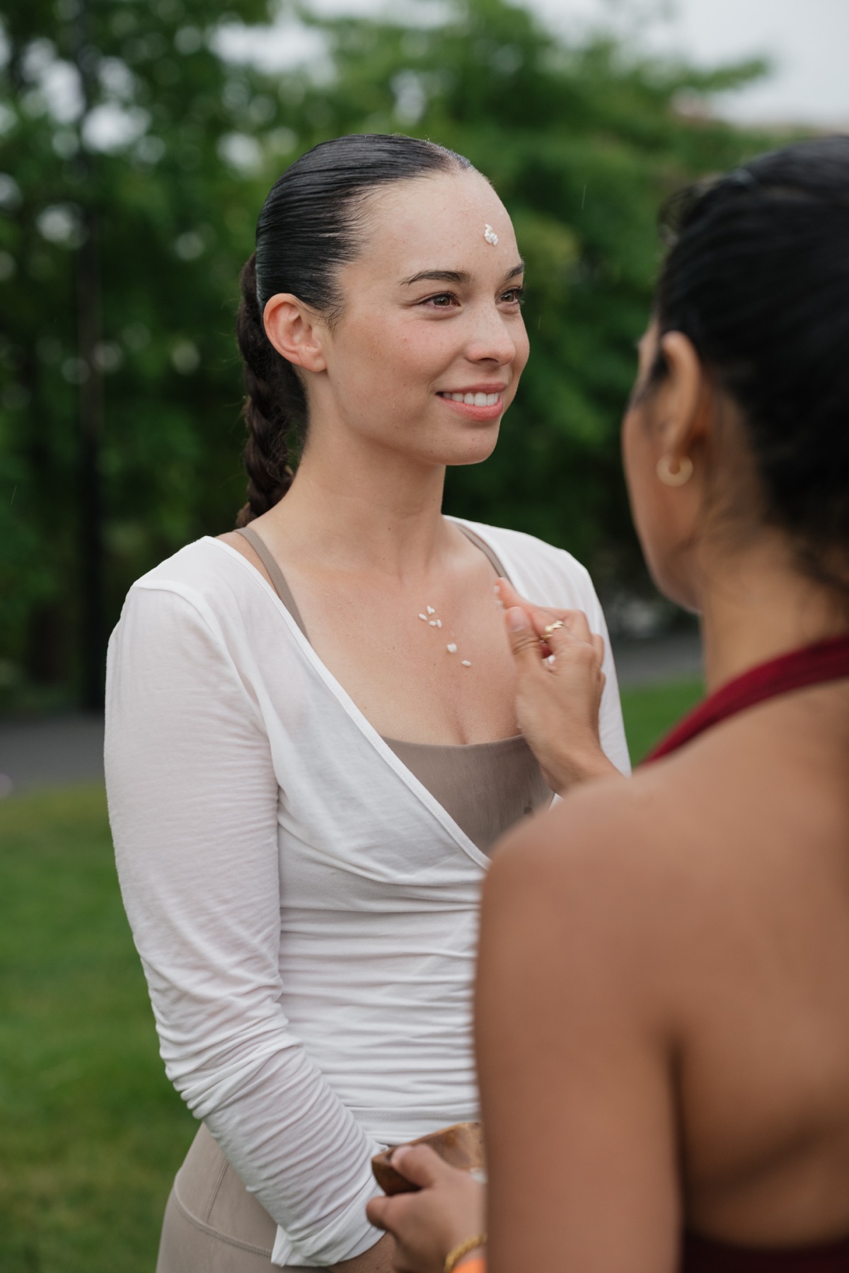 A woman receiving a bija rice blessing at Summer, Gently