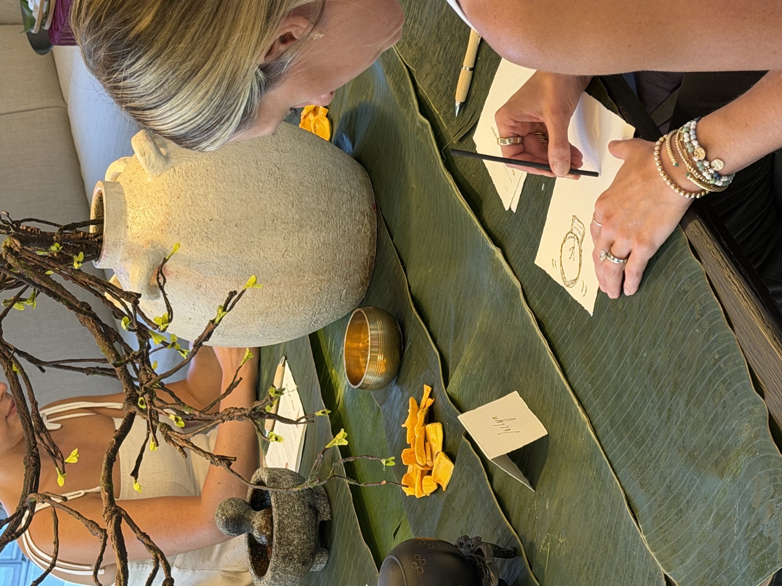 A woman drawing a charcoal portrait at the leaf-covered gathering table
