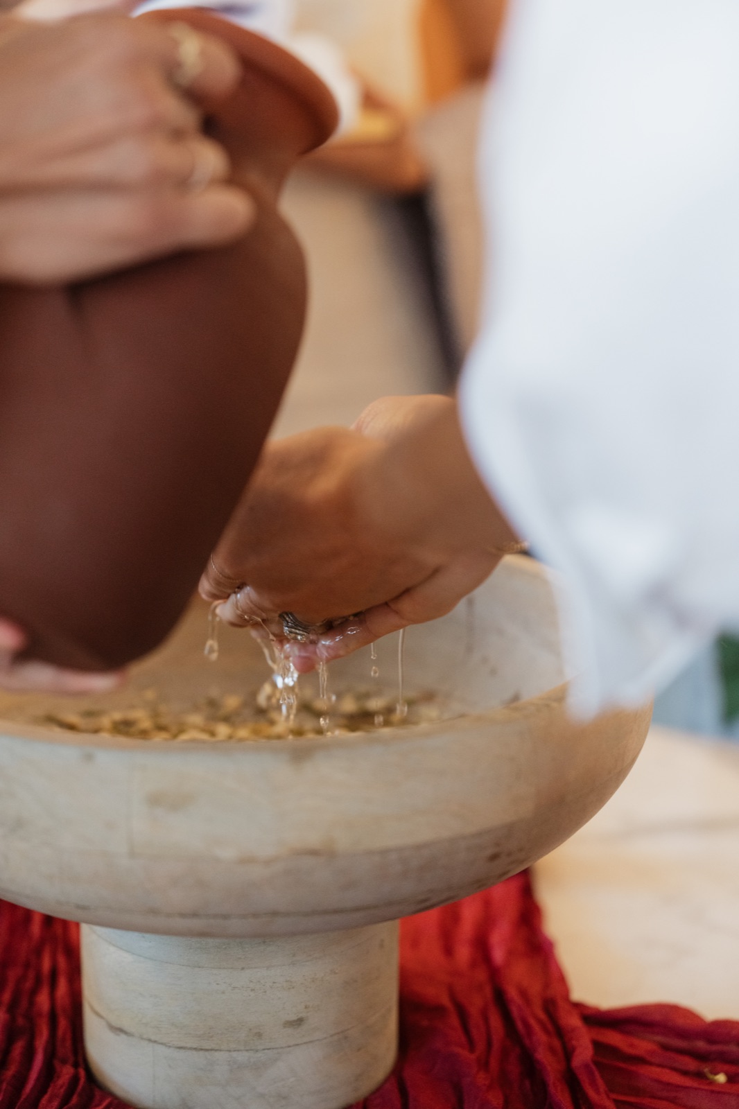 Close-up of water flowing over a guest’s hands into a stone basin during the hand-washing ritual