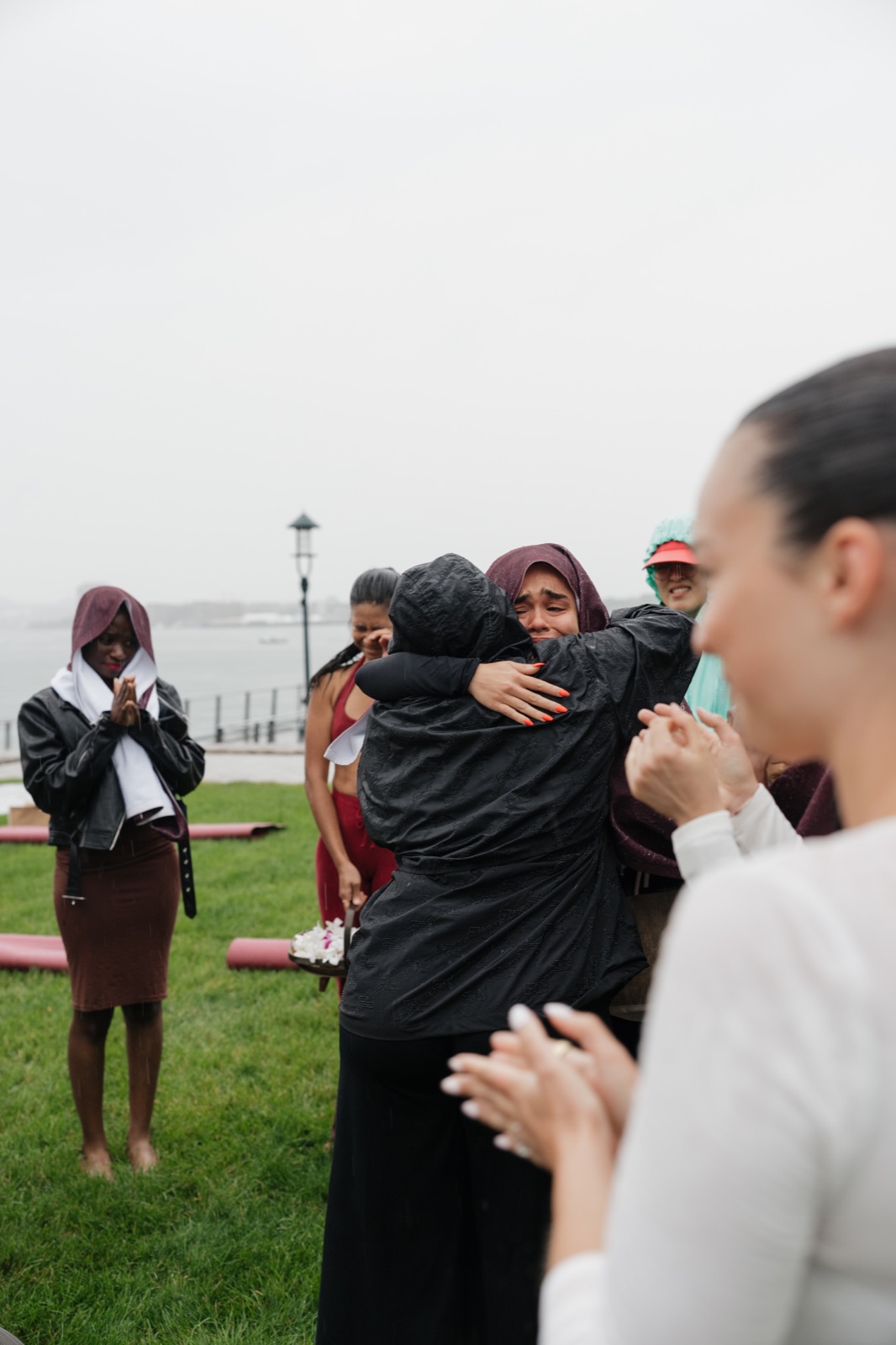 Two women embracing among the gathering on the rainy lawn