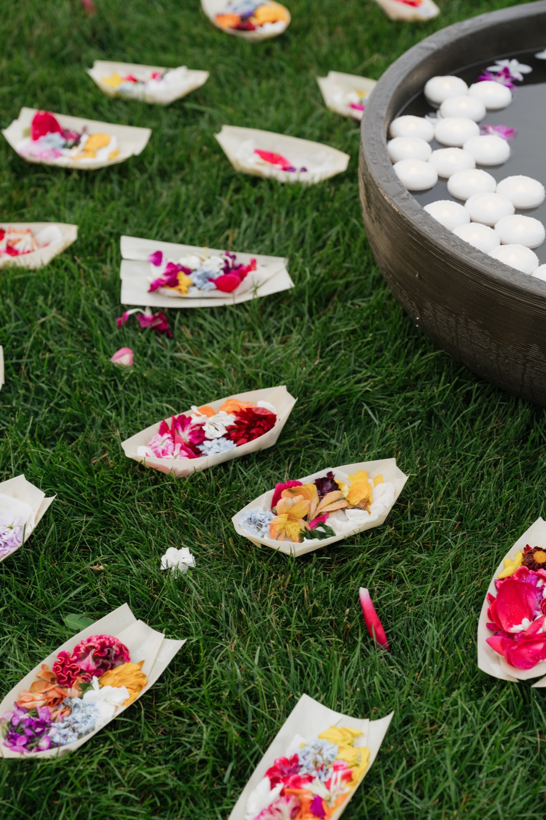 Flower offerings arranged on the grass beside a bowl of water
